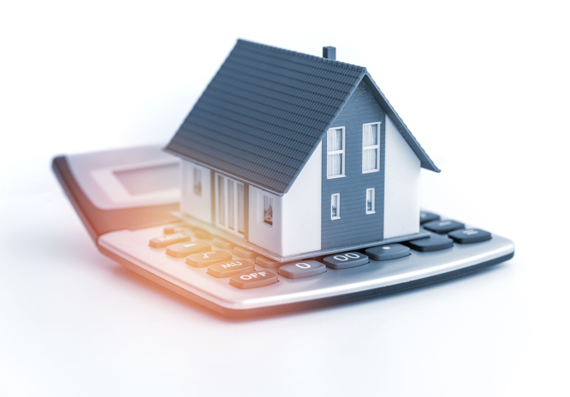 Miniature model house on a calculator on white background Miniature model house on a calculator on white background